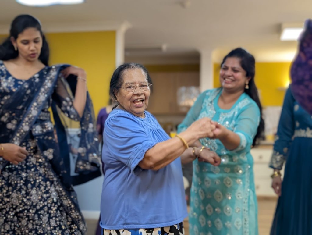 A resident and carer dancing at a Diwali evennt.